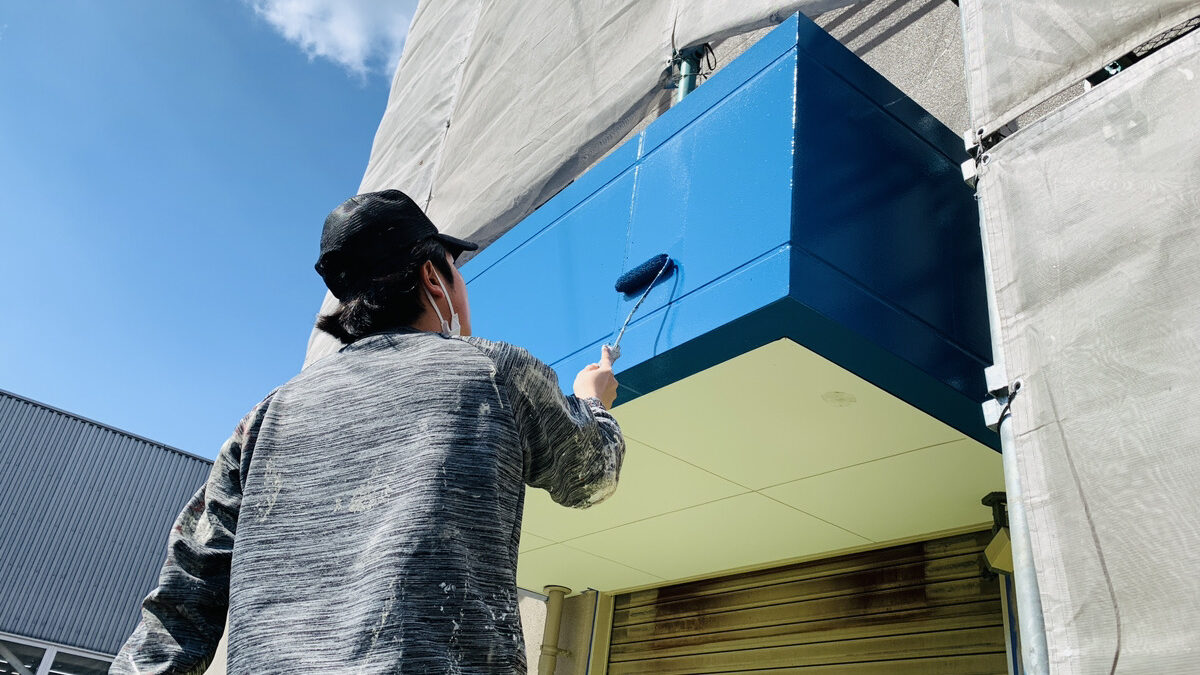 徳秀塗装の完全自社施工へのこだわり。職人が外壁を丁寧にローラーで手塗りしている作業風景