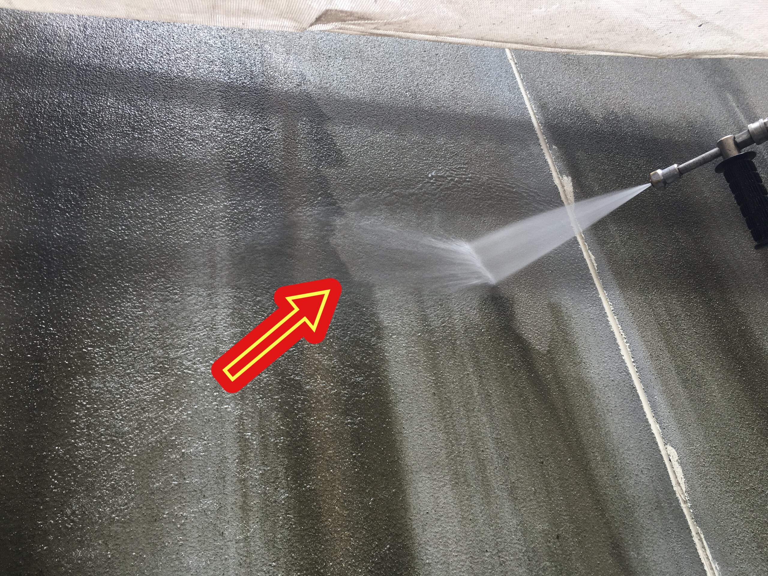 明石市相生の現場にて。ひび割れ補修の下地を整えるため、長年の汚れやコケを高圧洗浄で根こそぎ洗い流している作業風景です。