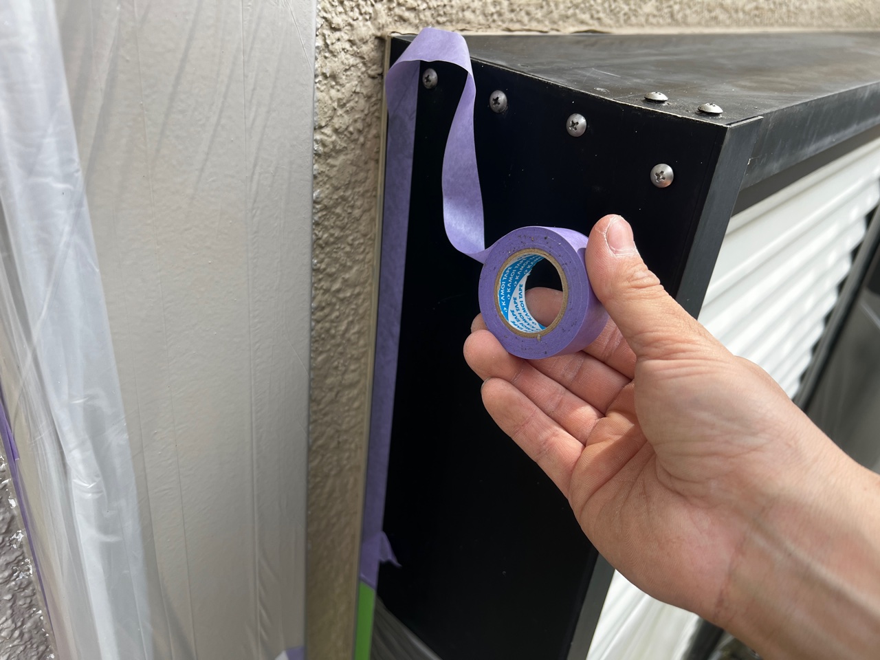 マスキングテープを貼る徳秀塗装の職人。見切りラインを美しく仕上げるための妥協しない作業風景です。