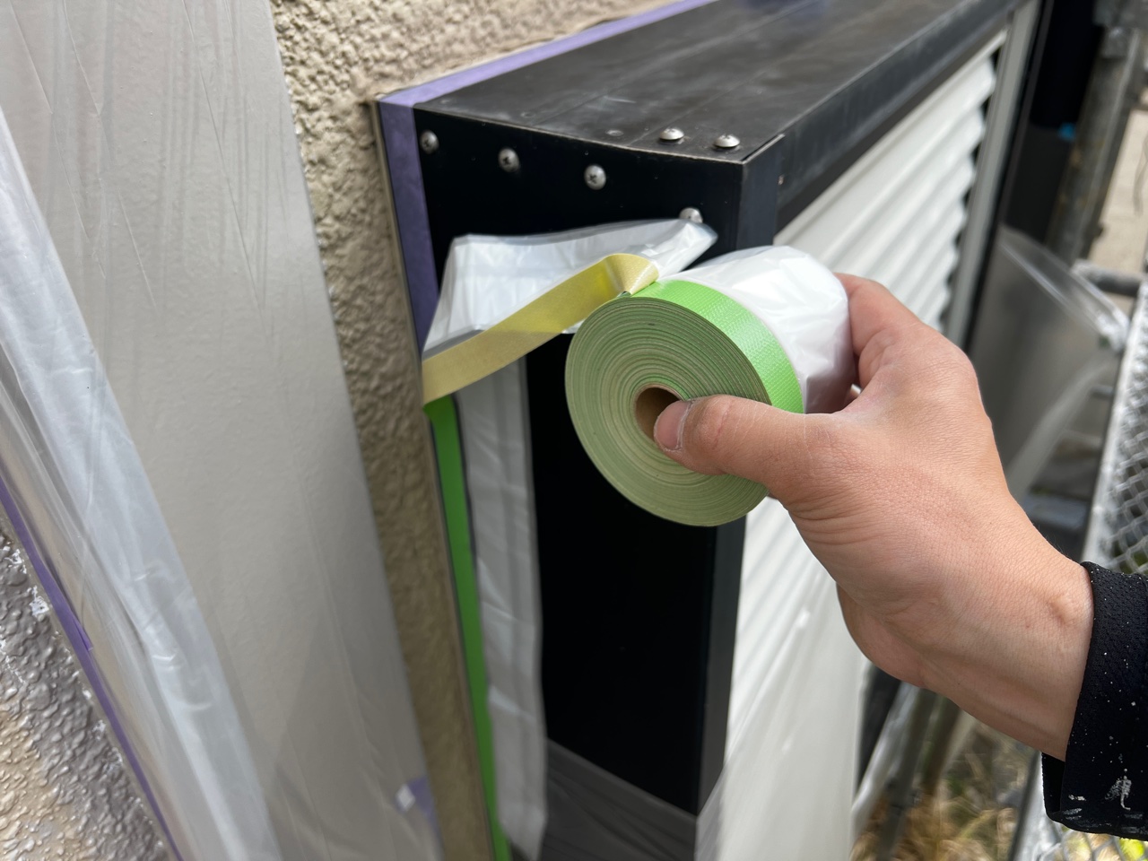 サッシ周りのマスキング養生が完了し、マスカーでの養生をしている様子。見えない下準備にも全力で取り組む、徳秀塗装の現場レポート。